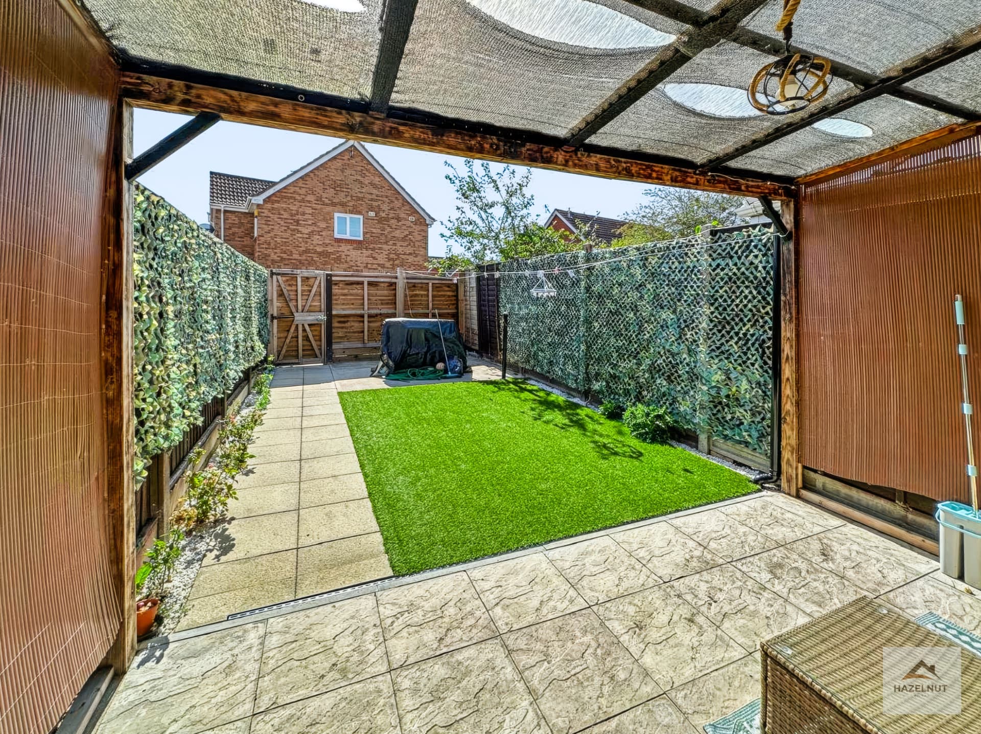 Private rear garden with covered pergola and artificial lawn at 8 Curlew Avenue